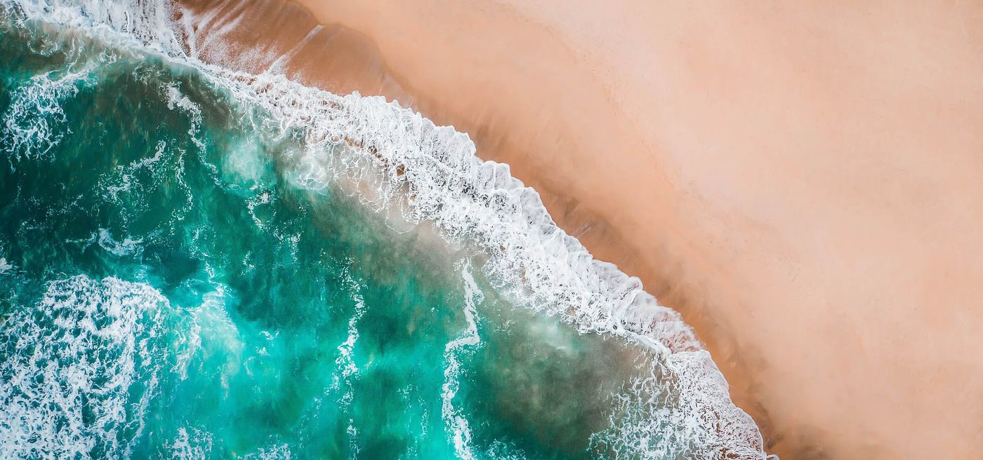 Aerial view of turquoise waves meeting a sandy beach